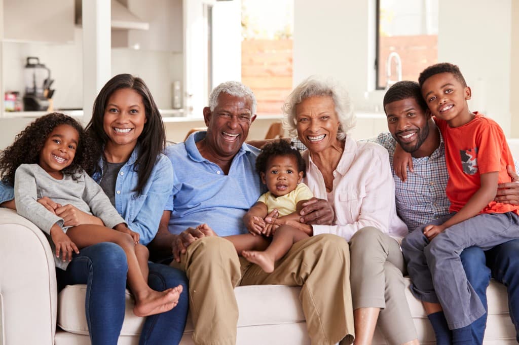 A multigenerational family sitting together on a sofa at home.